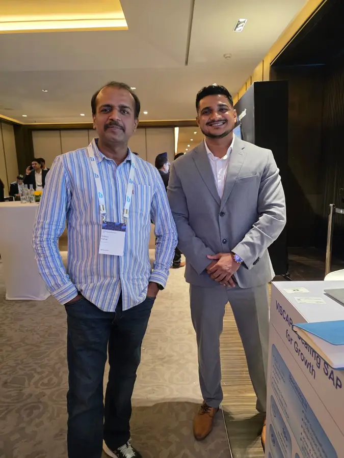 Un visiteur et un membre de l&rsquo;équipe VISCAP à côté du stand à SAP HR Connect Delhi.