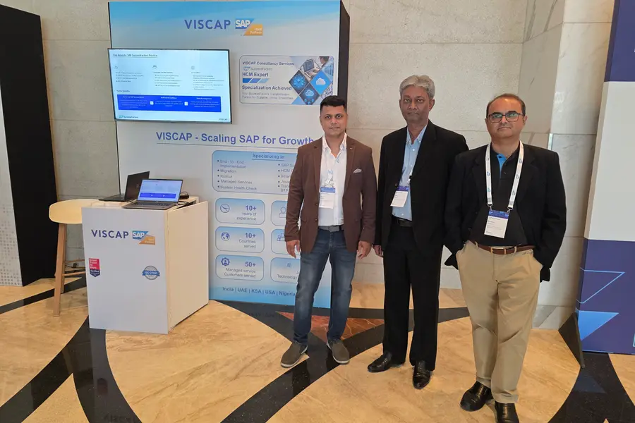 Three people standing beside the VISCAP stand.