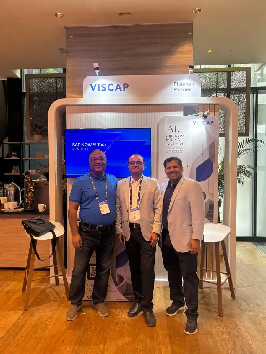 Three colleagues at the VISCAP stand in front of the SAP NOW AI Tour screen.